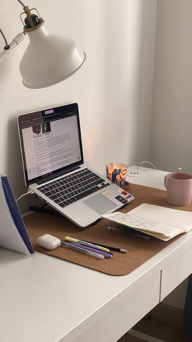 an open laptop computer sitting on top of a desk next to a cup and pen