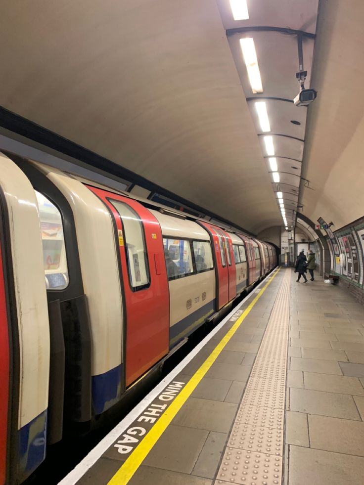 a subway train pulling into the station with people standing on the platform next to it