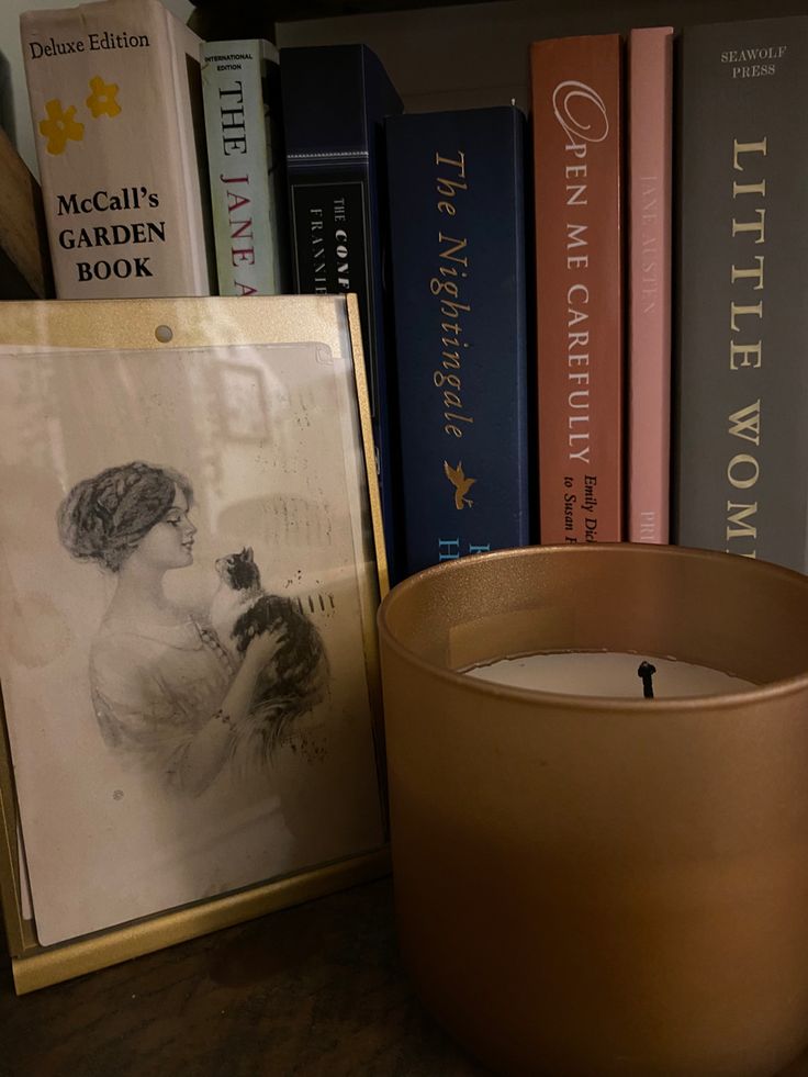 a candle sitting next to a book shelf with books on it and a framed photo