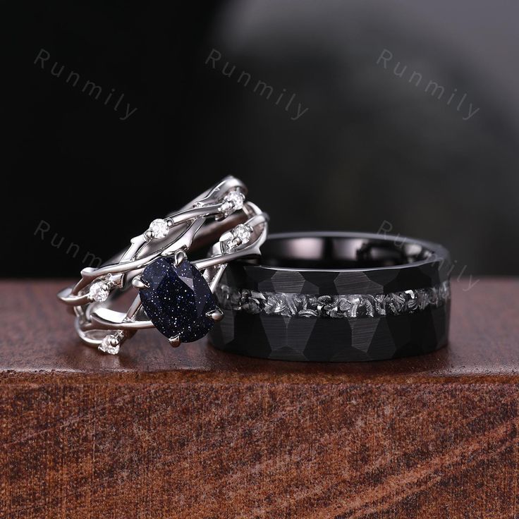 two wedding bands with black diamonds and blue sapphire stones on them, sitting next to each other