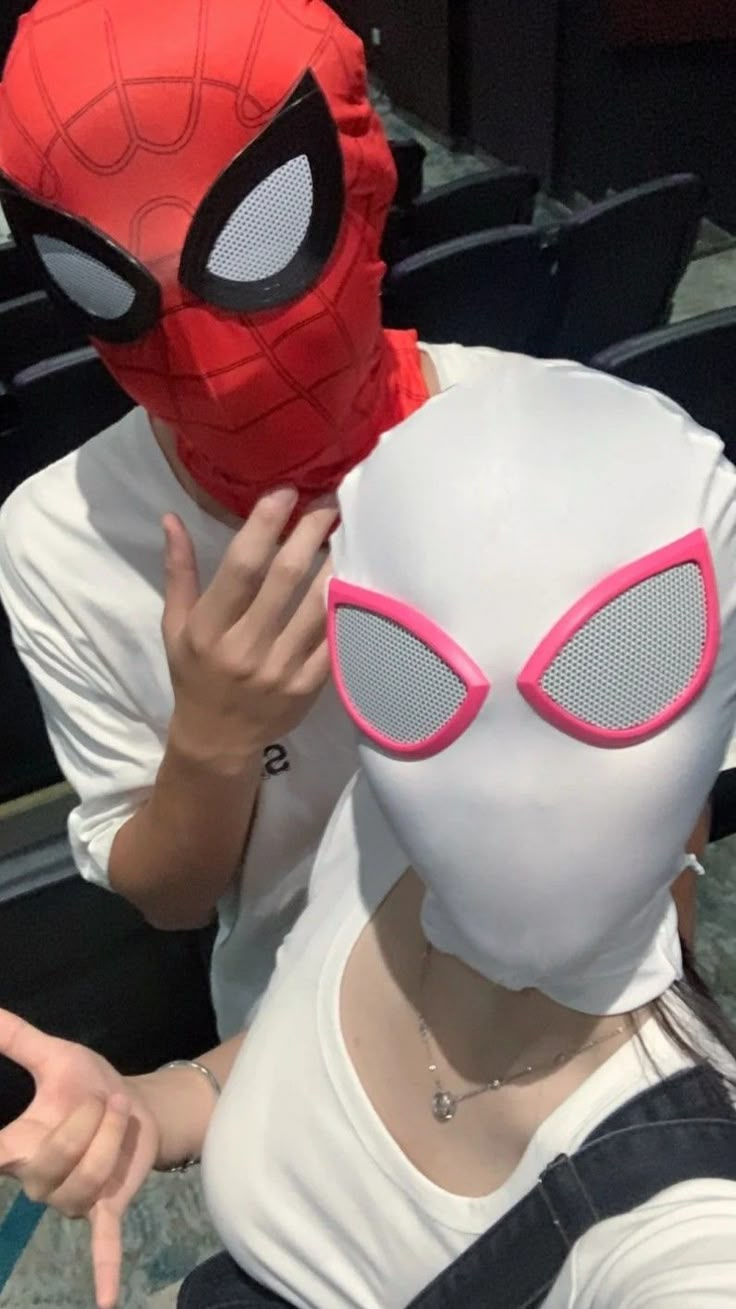 a person wearing a spiderman mask and covering their face with his hands while sitting in a chair