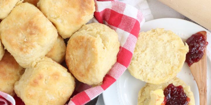 some biscuits and jam are on a plate next to a rolling pin with a wooden spatula