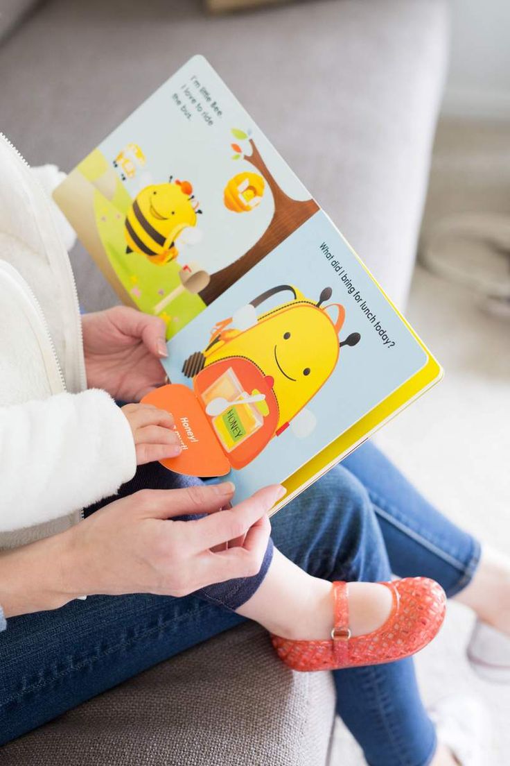 a woman is sitting on the couch reading a book to her toddler's feet