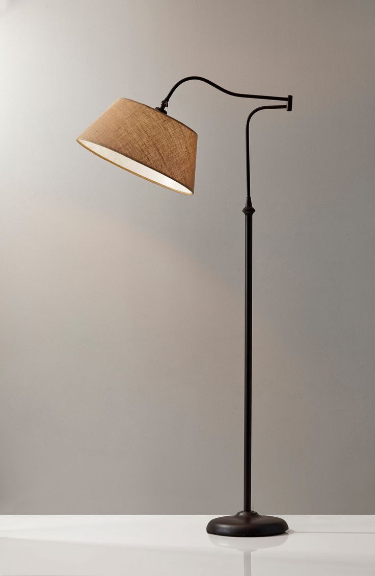 a floor lamp with a brown shade on the base and a white wall behind it