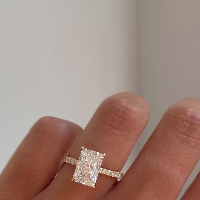 a woman's hand with a diamond ring on top of her finger and an engagement band