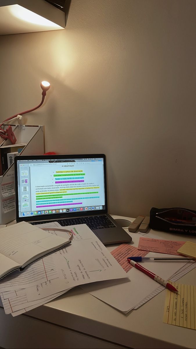 an open laptop computer sitting on top of a desk next to papers and pencils