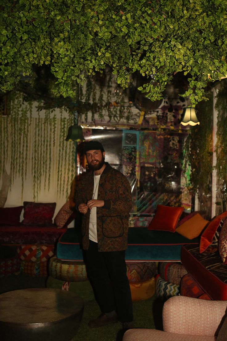 a man standing under a tree in a room filled with couches and tables,