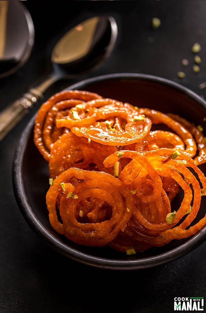 a bowl filled with sliced onion rings on top of a black table next to utensils