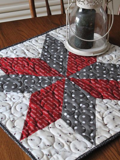 a quilted table topper with a lantern on it