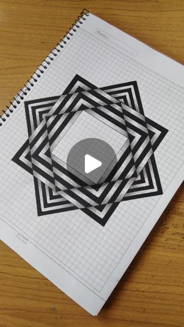 a spiral notebook with an image of a square in the middle on top of it