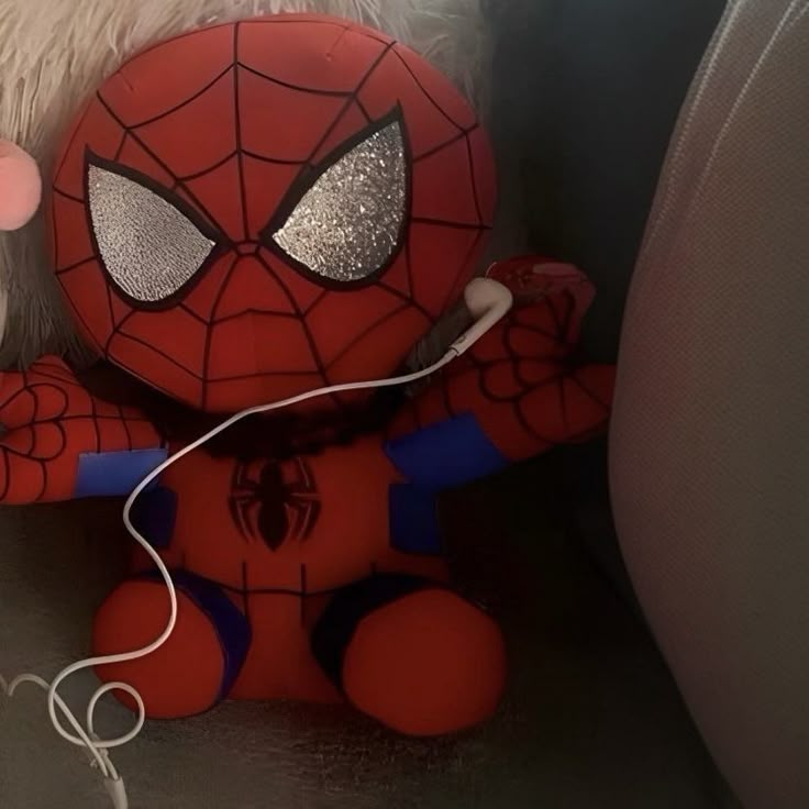 a spiderman stuffed animal sitting on top of a couch next to a remote control