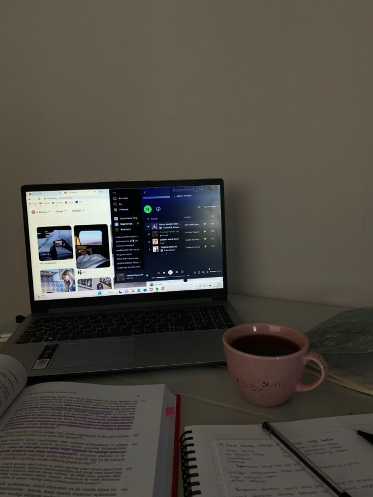 an open laptop computer sitting on top of a desk next to a cup of coffee