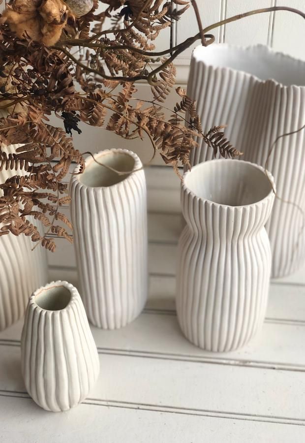 four white vases sitting next to each other on a table