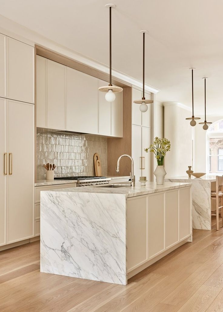 a large kitchen with marble counter tops and white cabinetry, along with wooden flooring