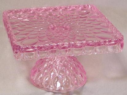 a pink glass cake stand on a white table