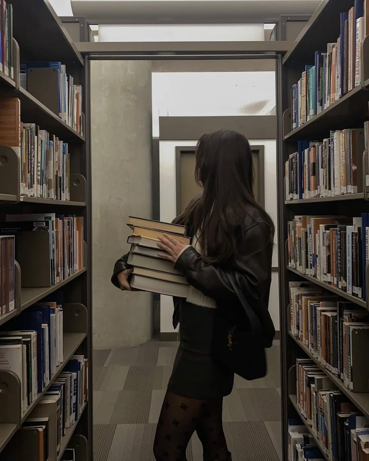 a woman is standing in the library holding several books