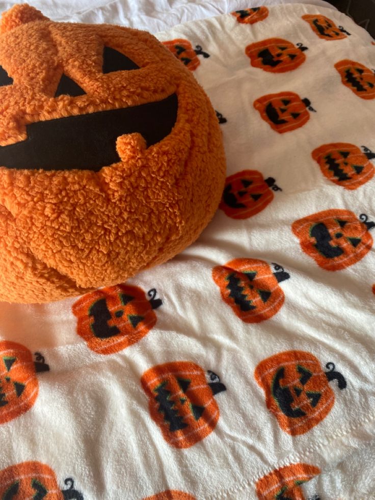 a stuffed pumpkin sitting on top of a bed