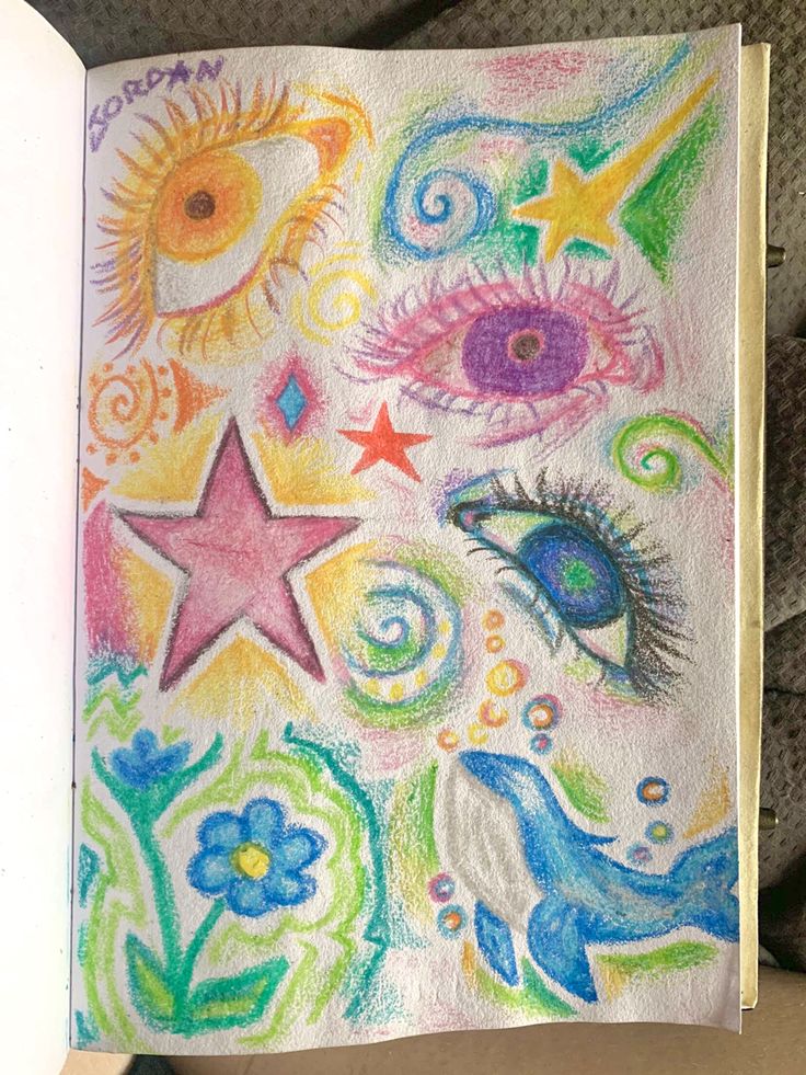 an open book with colored drawings on it and stars, fish, and flowers in the background