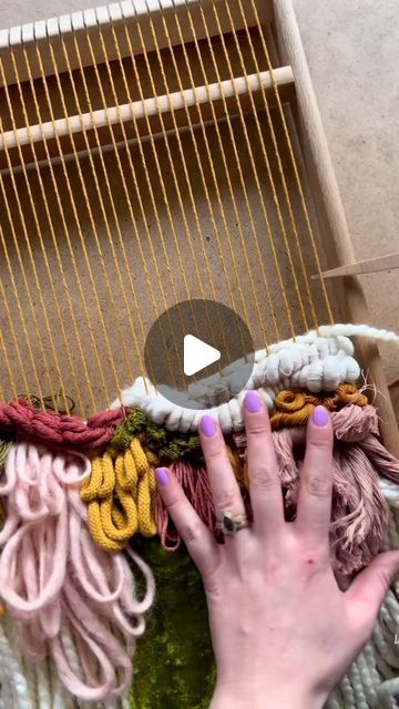 a woman's hand is touching the yarn on a loom with her fingers