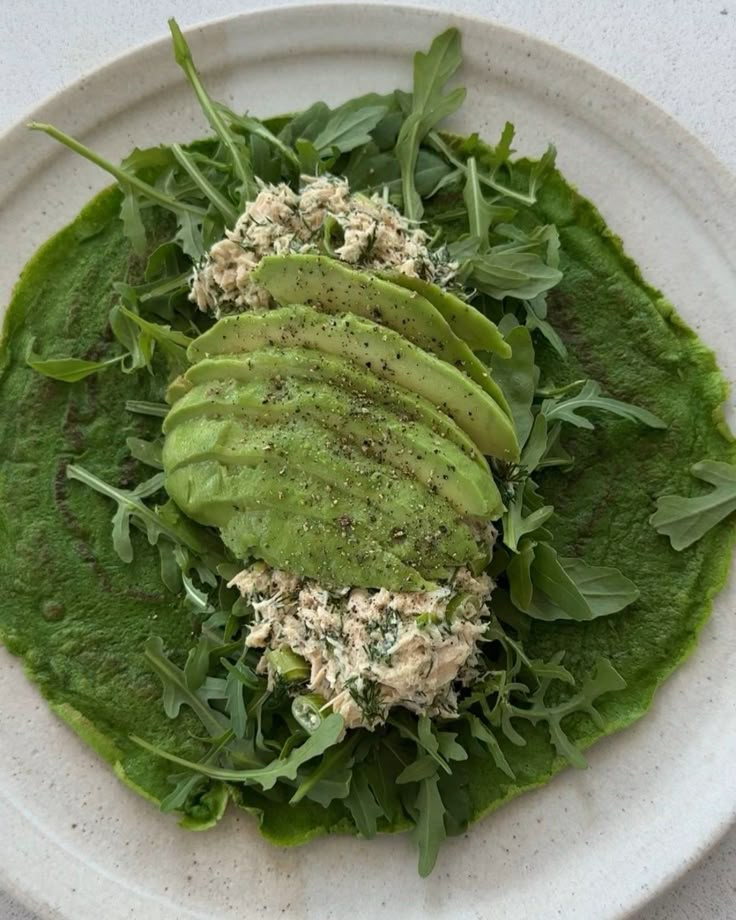 a white plate topped with spinach covered in sauce