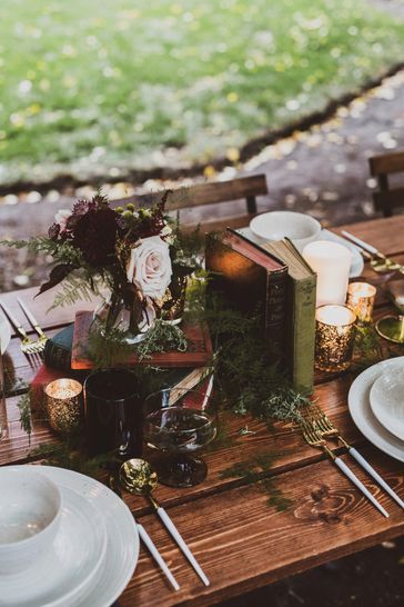 the table is set with books, candles and flowers for an outdoor dinner or party