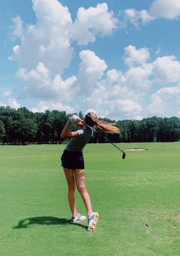 a woman is swinging her golf club on the green