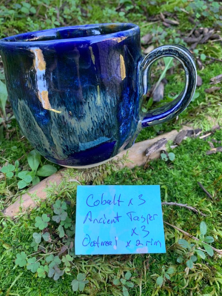 a blue mug sitting on top of a lush green field