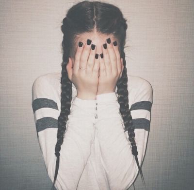 a woman covering her face with both hands while wearing black and white striped sweaters