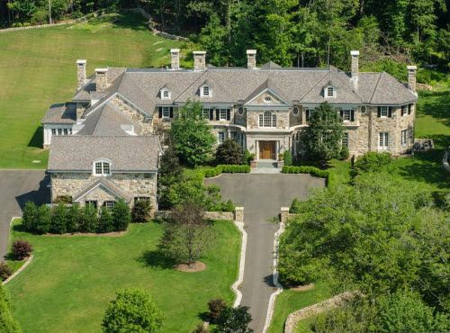 an aerial view of a large house in the middle of a wooded area with lots of trees