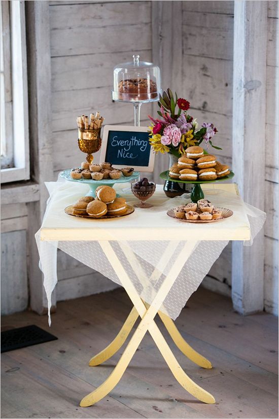 a white table topped with lots of pastries and desserts next to a window