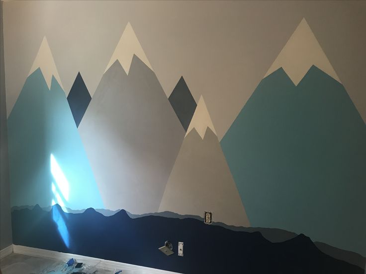 a bathroom with mountains painted on the wall next to a sink and toilet paper dispenser