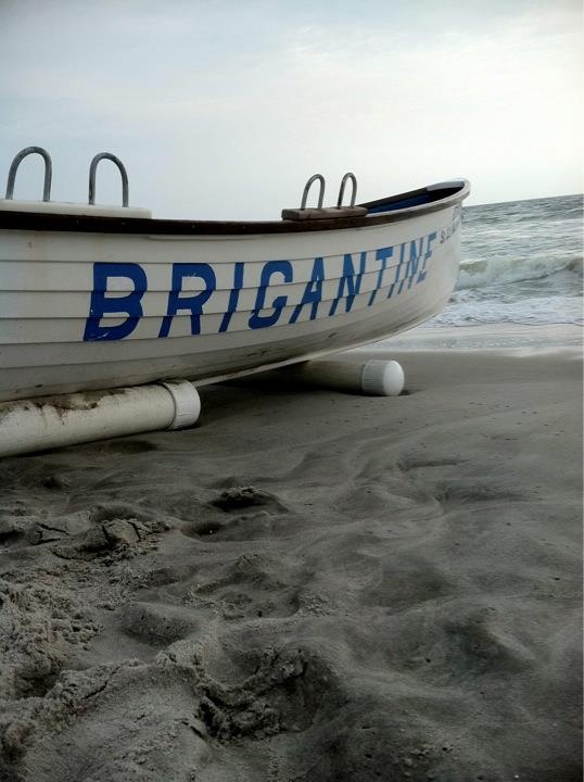 a white boat sitting on top of a sandy beach next to the ocean and waves