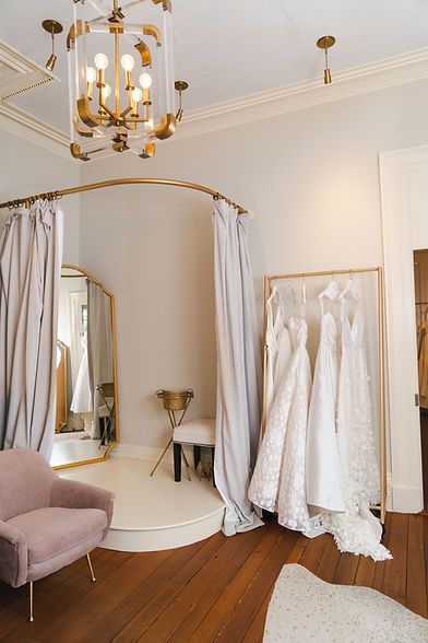 wedding gowns are hanging in the bridal room with chandelier and chair