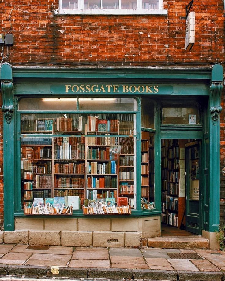 an old brick building with a bookshop on the front and windows filled with books