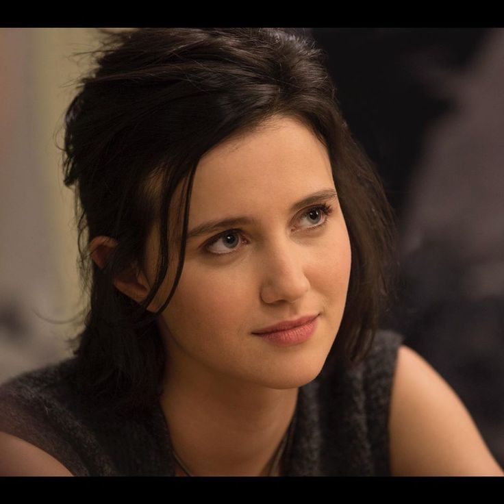 a close up of a person sitting at a table with a drink in front of her