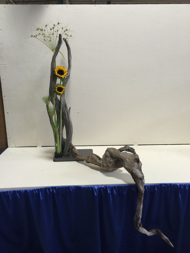 a wooden branch with sunflowers on it sitting on top of a blue table cloth