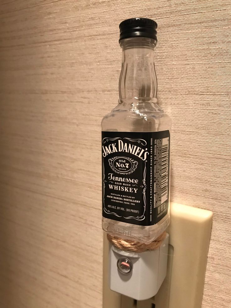 a bottle hanging on the side of a wall mounted toothbrush dispenser