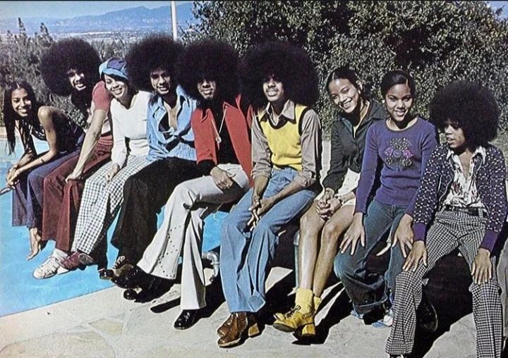 a group of people sitting next to each other on top of a cement slab in front of trees