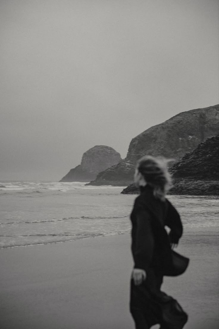 black and white photograph of woman running on beach with ocean in the backgroud