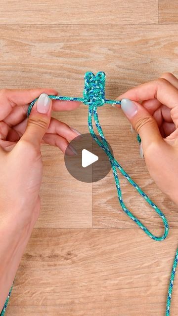 two hands tying a string together on a wooden surface