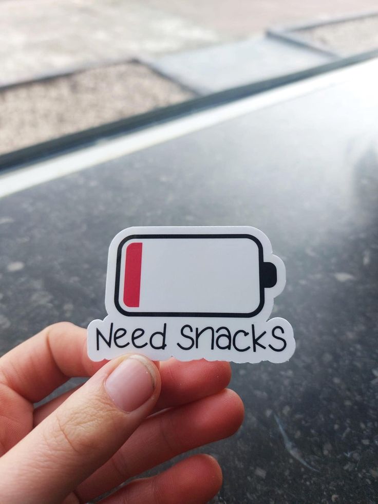 someone holding up a sticker that says need snacks