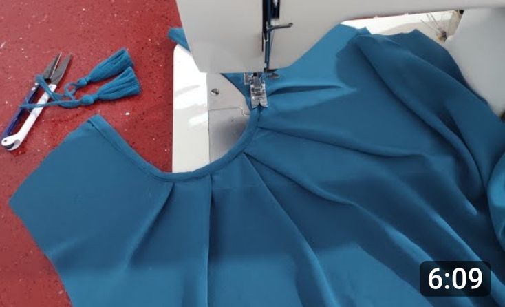 the sewing machine is working on the blue dress