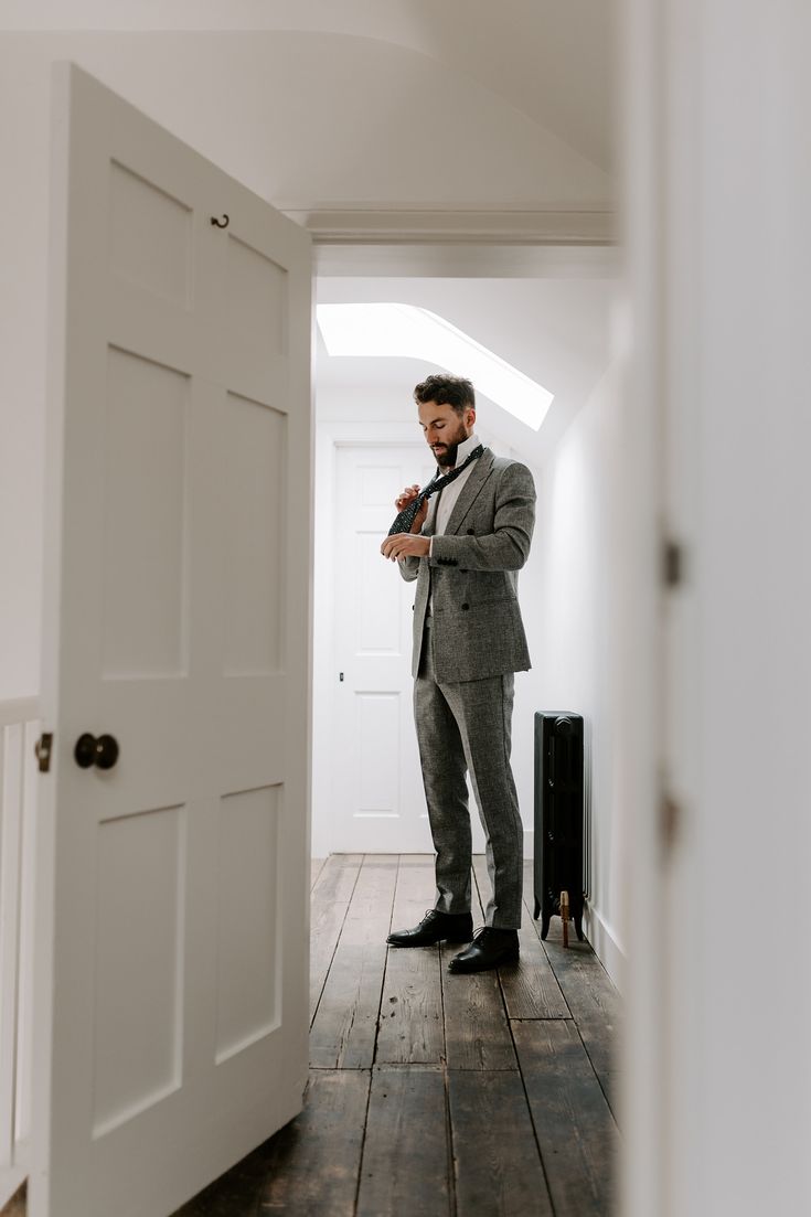 a man in a suit is standing by the door and looking at his cell phone