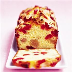 a loaf of cake on a white plate with almonds and raspberry topping