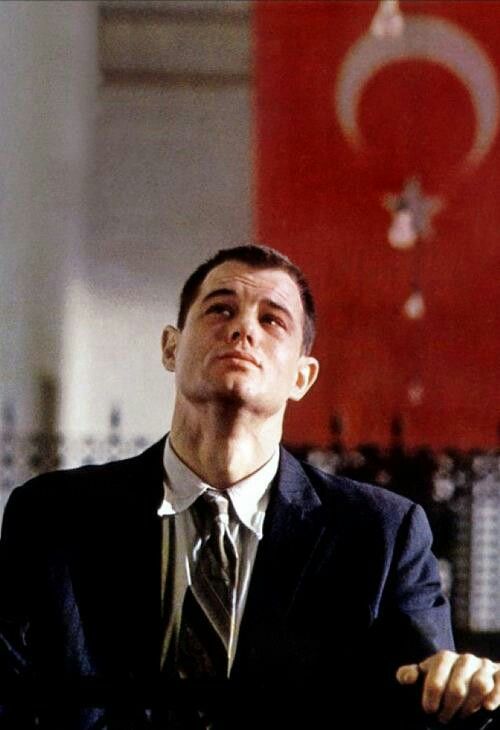 a man in a suit and tie sitting at a table with his arms crossed looking up