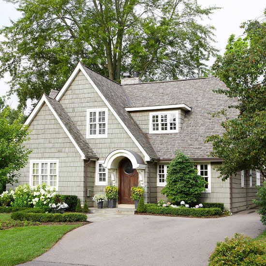 a gray house with white trim and two large windows on the front door is surrounded by greenery