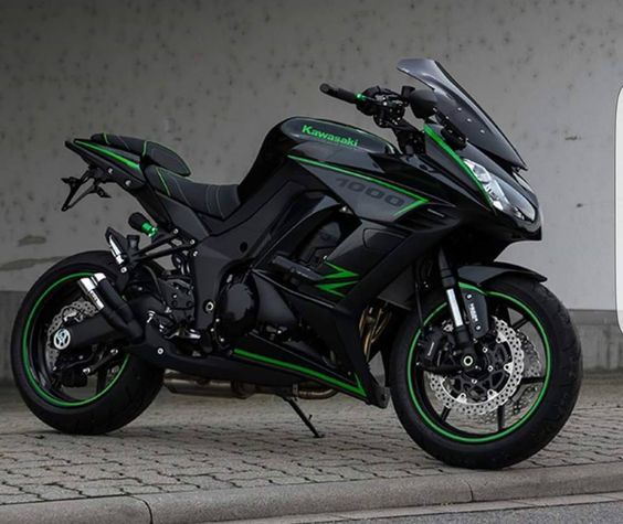 a black and green motorcycle parked next to a gas pump