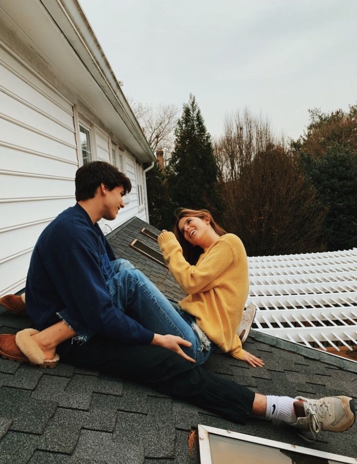 two people sitting on the roof of a house