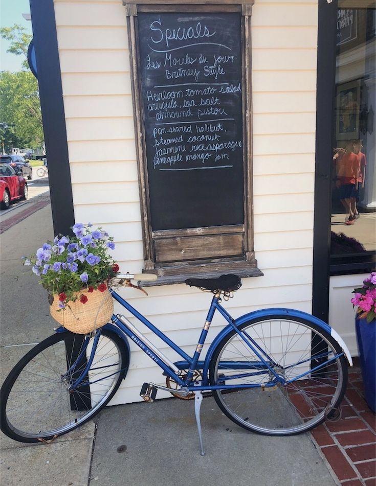 a blue bicycle parked in front of a building with a chalkboard attached to it