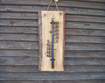 a wooden thermometer hanging on a wall next to a wood paneled building